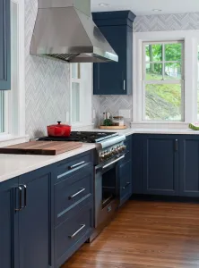 Modern kitchen with navy cabinets and red pot.